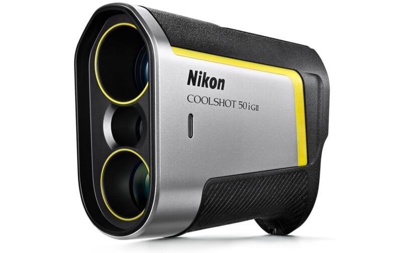 The image shows a Nikon Coolshot 50i GII rangefinder. It has a sleek, modern design with a silver body, black accents, and a yellow trim. The device features two lens openings on the front and is angled slightly to the left.