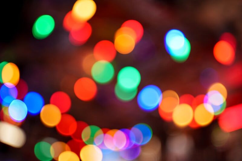 A blurred image displaying colorful bokeh lights in various bright colors, including red, green, blue, and yellow, creating a festive and vibrant atmosphere.