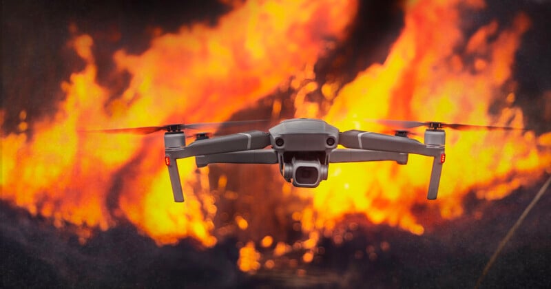 A drone hovers in the foreground with large flames blazing in the background, creating a dramatic contrast between the technology and the fire. The fiery scene suggests urgency or action.