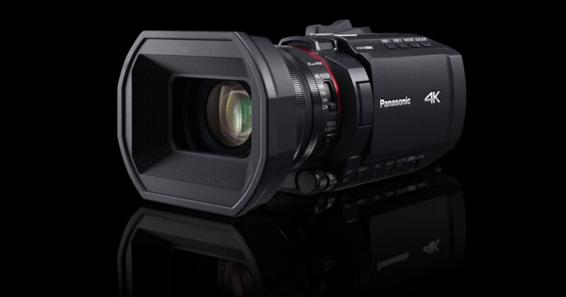 A black Panasonic 4K video camera with a large lens shown against a black background, highlighting the camera's features and design.