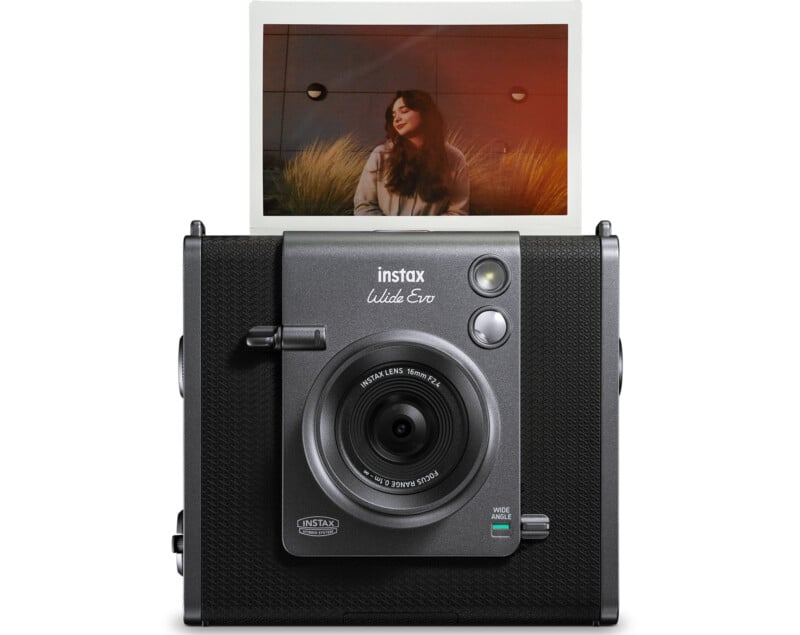 The image shows a Fujifilm Instax Wide Evo instant camera with a developed photo emerging from the top. The photo features a person with long hair sitting in front of a wall and grass, bathed in warm light.