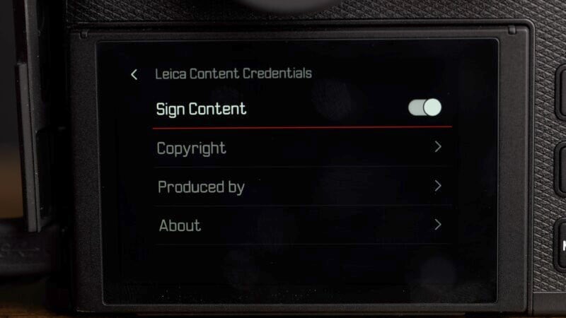 A close-up of a camera screen displaying menu options under "Leica Content Credentials," including "Sign Content," "Copyright," "Produced by," and "About." The "Sign Content" toggle is turned on.