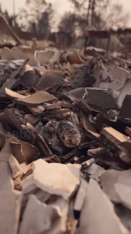 A close-up view of a pile of charred debris with scattered remnants of burned building materials and ash, highlighting the aftermath of a fire.