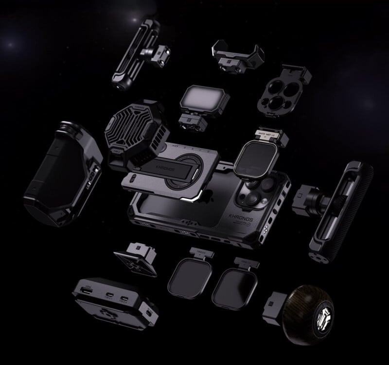 A futuristic assembly of modular gadgets and components, predominantly in black, floating against a dark background. Parts include various camera lenses, connectors, and electronic modules.