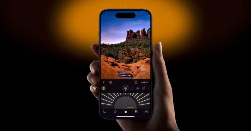 A hand holds a smartphone displaying a photo editing app. The screen shows a vibrant image of a rocky landscape with trees under a starry sky. The background is a dark gradient, transitioning from orange at the top to black below.