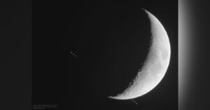 A crescent moon is prominently displayed against a dark background. Multiple small, circular objects are visible near the moon's edge, aligned vertically. The image captures a celestial scene with detailed lunar surface textures.