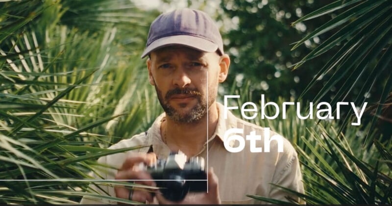 A man in a light-colored shirt and cap is holding a camera surrounded by green foliage. The text "February 6th" is overlaid on the image in white.