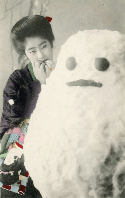 A vintage photo of a person with an elaborate hairstyle wearing a traditional outfit, standing next to a snowman. The snowman has round eyes and a simple mouth. The person is playfully interacting with the snowman.