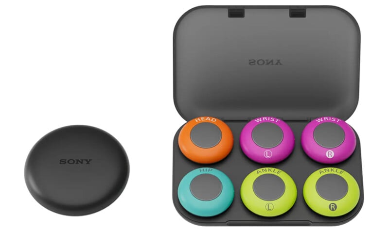 A black Sony case containing six colorful circular sensors labeled "Head," "Wrist L," "Wrist R," "Hip," "Ankle L," and "Ankle R." Each sensor is a different color, and there's an additional closed circular case next to it.