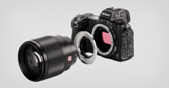 A Nikon Z series mirrorless camera with an exposed sensor is shown alongside a detached camera lens and an adapter ring. The camera body, lens, and ring are aligned on a plain background.