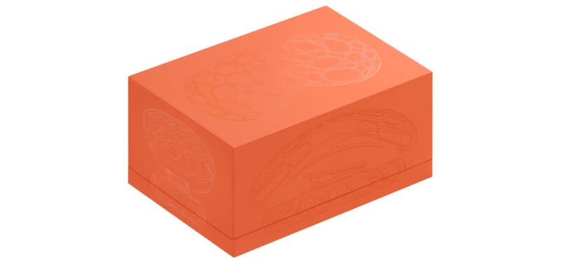 An orange box with embossed patterns on its top and sides, featuring a design of rounded shapes and curves. The patterns appear intricate and decorative. The box is set against a white background.