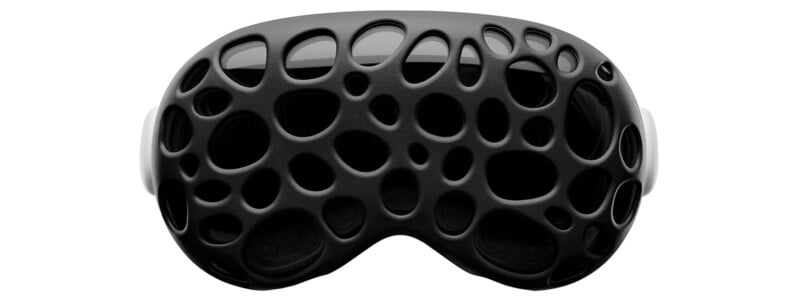 A pair of black goggles with a unique, open lattice structure resembling organic, irregular patterns. The design showcases multiple rounded openings, giving it a futuristic and dynamic appearance.