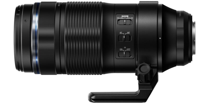 A black telephoto camera lens with a rotating tripod mount, displayed horizontally. It features various switches for settings adjustments, including focus modes and image stabilization, with visible zoom rings and an electronic mount.