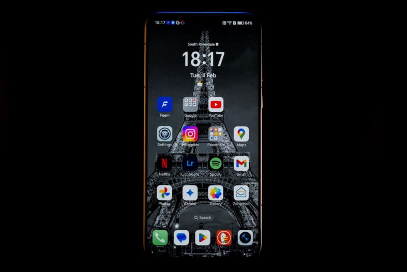 Smartphone displaying various app icons on the home screen, including Instagram, YouTube, and Google Maps, with a monochrome Eiffel Tower wallpaper. The time shown is 18:17 on a Tuesday in February.