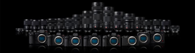 A lineup of Panasonic Lumix cameras and lenses arranged against a black background. The cameras are positioned in the front with various lenses of different sizes displayed behind them.