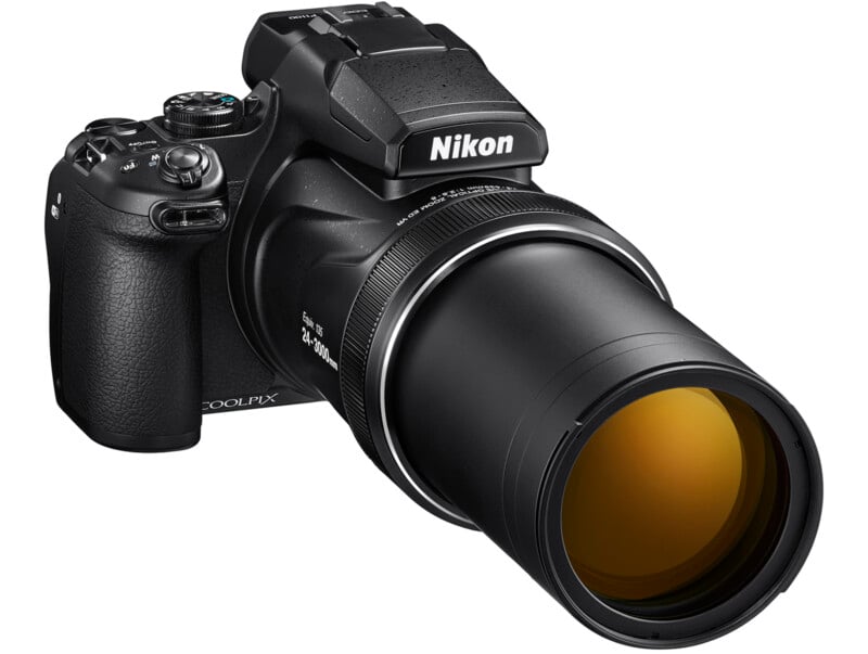 Uma câmera preta da Nikon Coolpix com uma lente de zoom estendida. A câmera apresenta vários mostradores e botões na parte superior e no lado e tem uma grande aderência à esquerda. A lente é estendida com destaque com uma lente objetiva de tons amarelos.