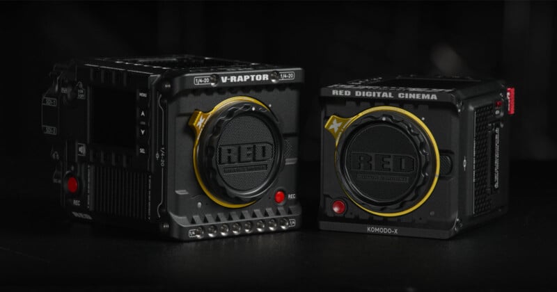 Two black RED digital cinema cameras, model V-RAPTOR and KOMODO-X, against a dark background. Both cameras feature prominent RED branding and yellow accents around the lens mounts.