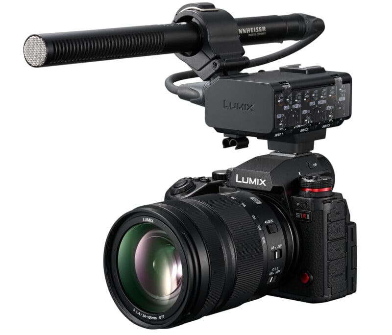 A Lumix S1R camera with a large zoom lens and an external Sennheiser microphone attached on top. The setup is professional and geared for high-quality audio and photography.