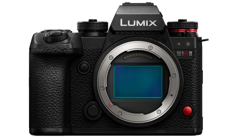 Front view of a Lumix S1R II camera without a lens attached. The body is black with textured grip, featuring various control dials and buttons. The camera's sensor is visible, along with a prominent brand logo on top.