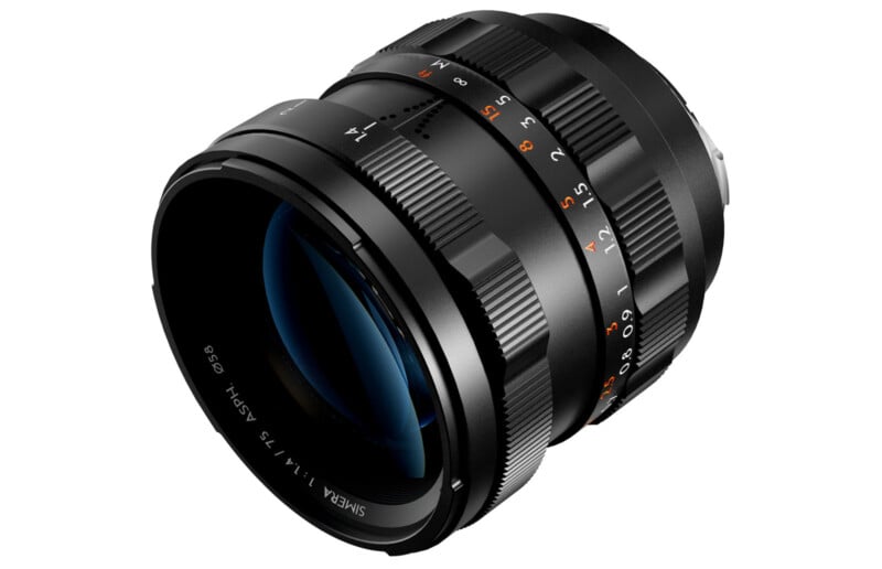 A black camera lens with orange and white markings is shown at an angle. The lens has various adjustment rings with engraved numbers, including focus and aperture settings. The front rim displays text indicating specifications.