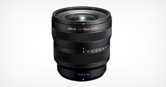 Wide-angle camera lens with black exterior, featuring "atx-m 11-18mm F2.8 X" labeling on the front. The lens has a textured focus ring and a blue "Tokina" logo at the base, set against a white background.
