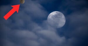 A basketball with a red arrow pointing to it is in the sky near a full moon, surrounded by clouds.