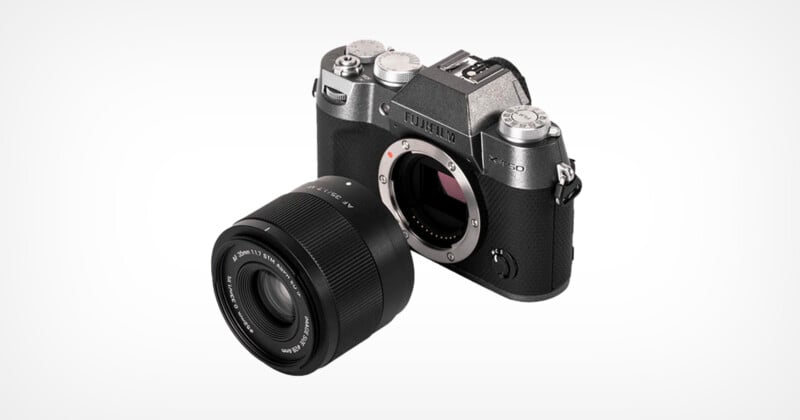 A Fujifilm camera body with retro styling is displayed alongside a detached lens on a white background. The camera has a textured grip and multiple dials, while the lens is shown with its front element facing the viewer.