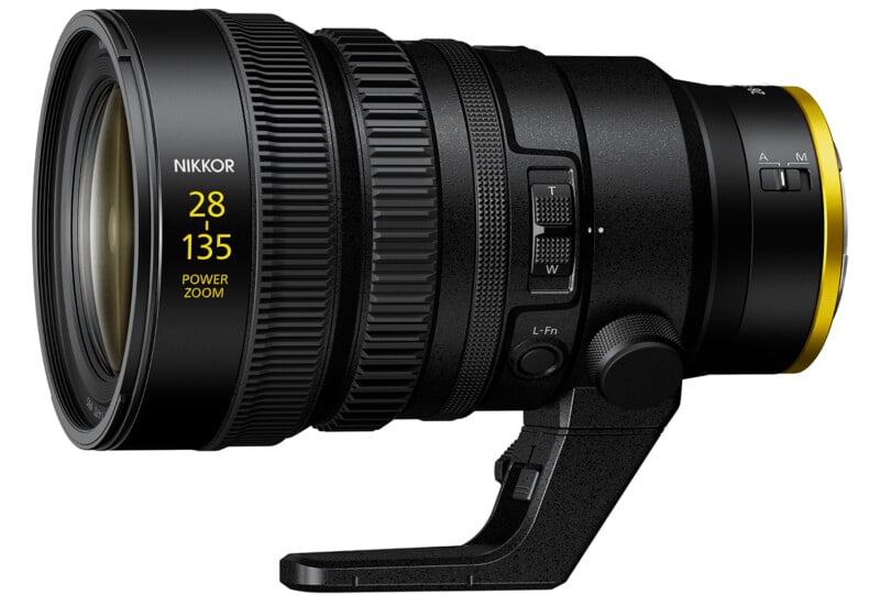 A black Nikkor 28-135mm power zoom lens with a black tripod mount. The lens has focus and zoom adjustment rings, control switches, and a yellow accent near the end.