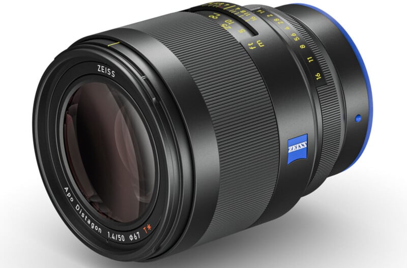 Close-up of a Zeiss camera lens with a black body, blue accent, and yellow markings. The text on the lens reads "Apo Distagon 1.4/50" and features a blue Zeiss logo. The lens is tilted slightly to the left.