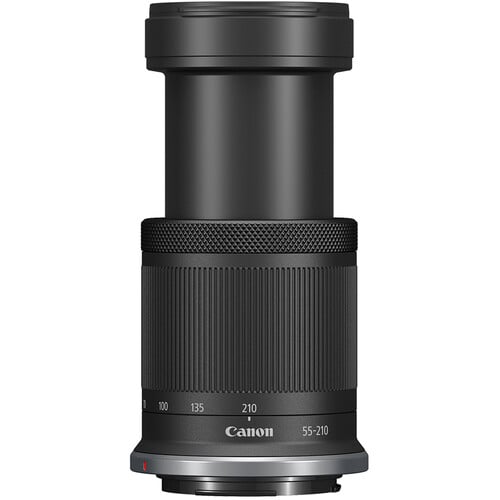 A black Canon lens with extended zoom, featuring ribbed grip sections, focus distance markings in white, and a focal length range from 55 to 210mm.