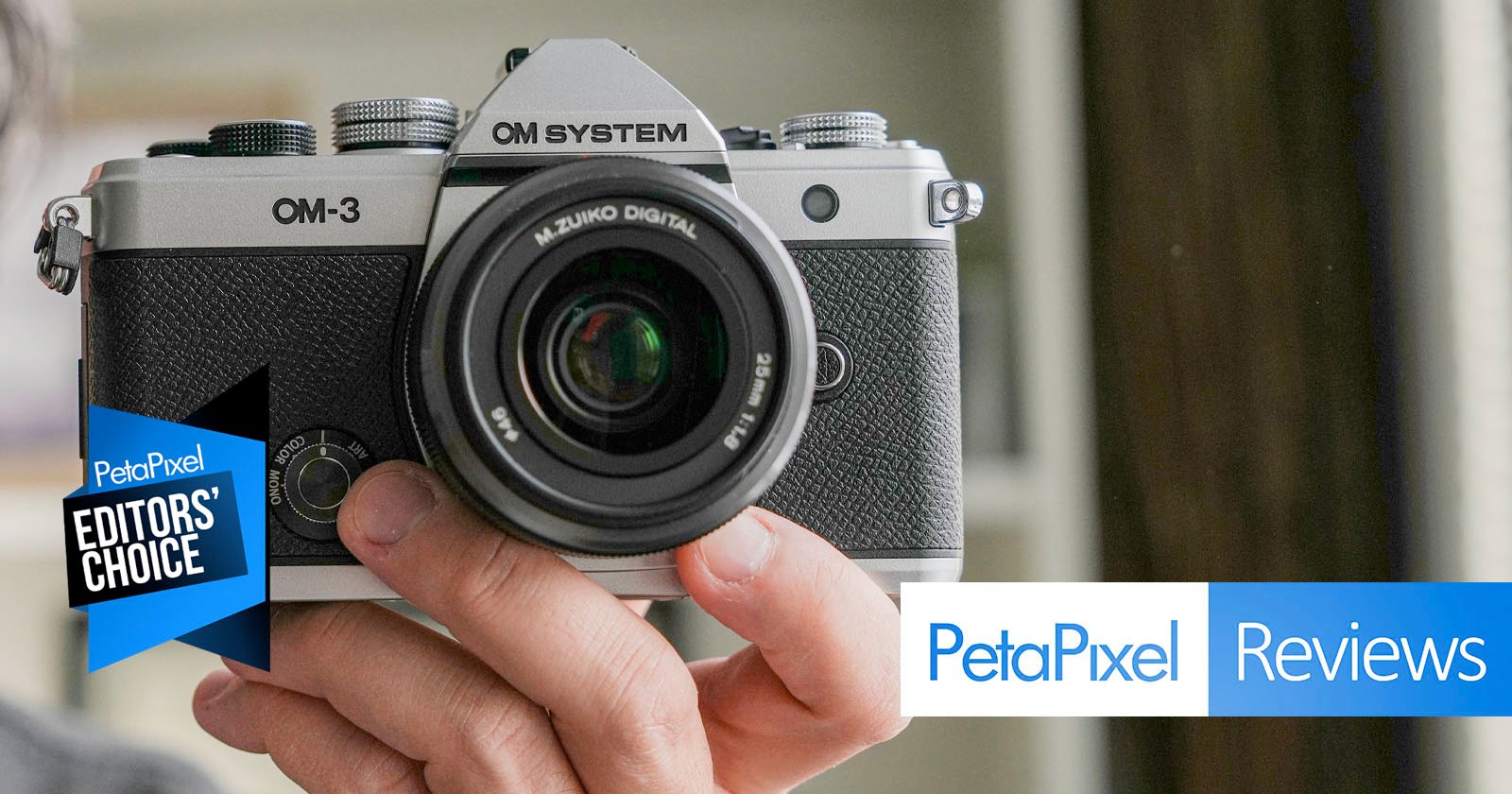 A person holds an OM System OM-3 camera facing the viewer. The image features "Petapixel Editors' Choice" and "Petapixel Reviews" banners in the foreground.
