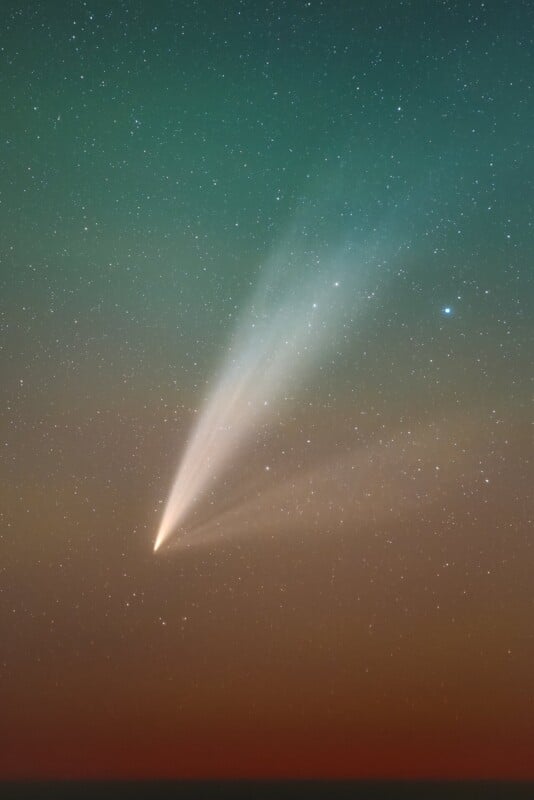 A bright comet with a glowing tail streaks across a starry night sky. The background is a gradient of green to red hues, adding a colorful contrast to the scene.