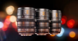 Three camera lenses labeled 50mm, 35mm, and 24mm are displayed side by side against a blurred background of colorful lights. The lenses have aperture markings and focus rings. The bokeh effect adds a vibrant contrast.