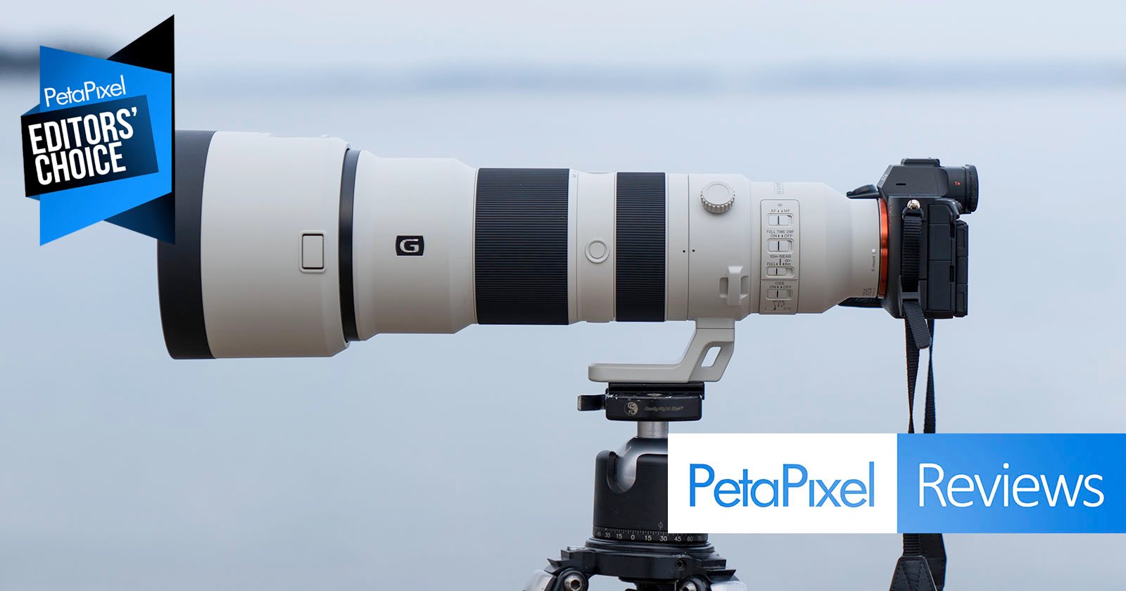 A large white Sony telephoto camera lens is mounted on a tripod with a camera attached, positioned outdoors against a blurred grayish-blue background. The image features a "Petapixel Editors' Choice" badge and "Petapixel Reviews" text.