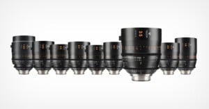 A series of black professional camera lenses with various focal lengths are aligned in a row on a white background. Each lens has detailed markings and numbers indicating the specifications.