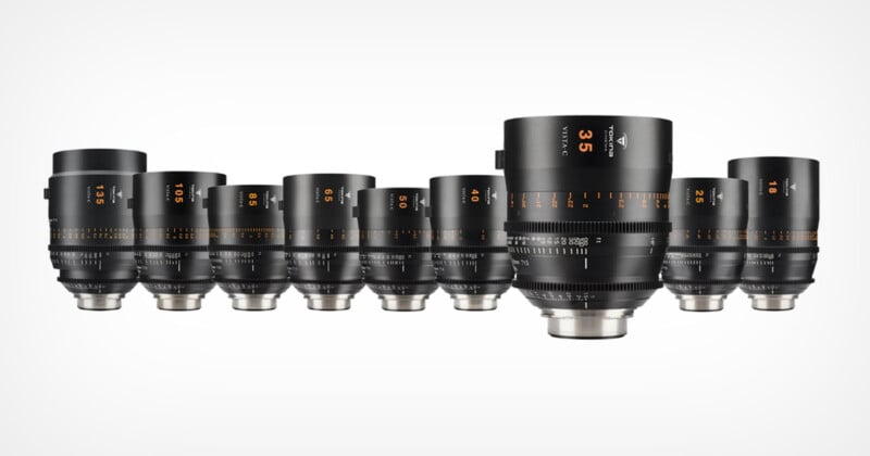 A series of black professional camera lenses with various focal lengths are aligned in a row on a white background. Each lens has detailed markings and numbers indicating the specifications.