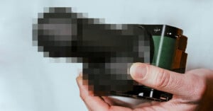 A person's hand holds a heavily pixelated object against a plain background. The image is intentionally blurred, obscuring details of the object.