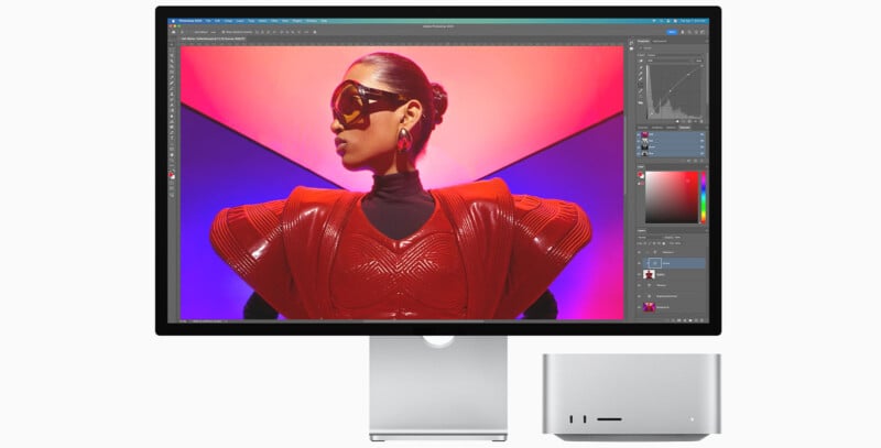 A sleek computer monitor displays graphic design software, showing an image of a person in futuristic red clothing and sunglasses. The setup includes a compact silver computer and a modern, minimalist stand.