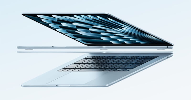 Sleek, silver laptop partially open against a light blue background. The design highlights the keyboard layout and the inner screen, showcasing a blue feathered pattern on the display.