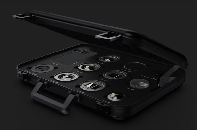 A black case on a dark background is open, revealing a variety of neatly arranged camera lenses and an empty phone slot. The case lid is slightly tilted, and it has a handle on the side.