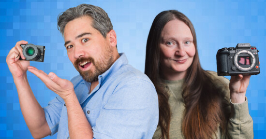 A man and a woman pose against a blue pixelated background. The man holds a small camera with an excited expression, while the woman holds a larger camera and smiles. Both wear casual clothing, emphasizing a photography theme.