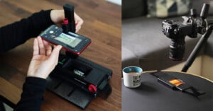 A person uses a smartphone with a mount to scan film negatives. Next to it, a digital camera is setup on a tripod for film scanning. A cup of coffee is on the table beside the equipment.