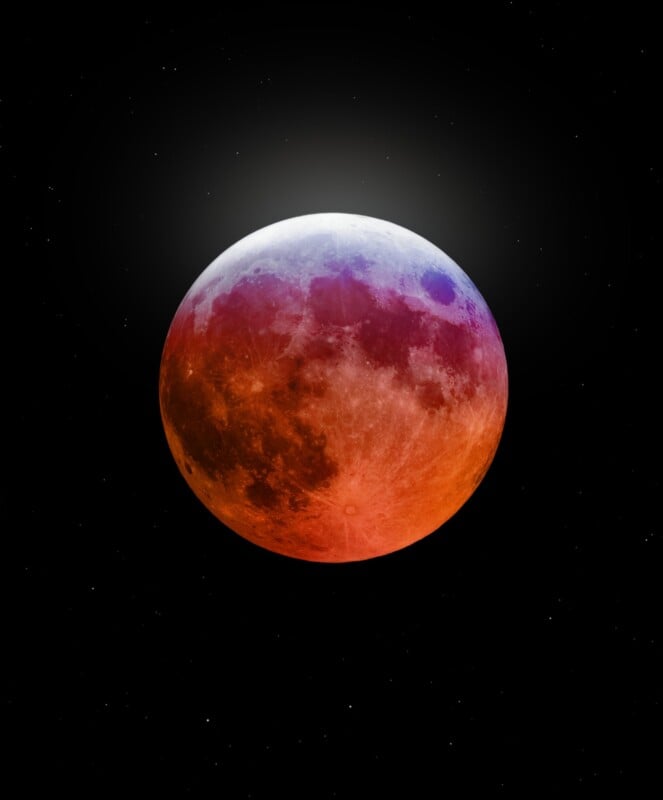 A vivid close-up of the moon during a lunar eclipse, displaying a striking color gradient from deep red at the bottom to a cooler blue and white at the top. The moon is set against a backdrop of a starry black sky.