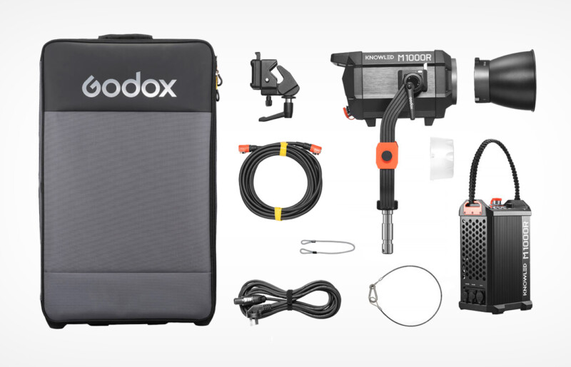 Photography lighting kit with a Godox case, M1000R light, cables, and accessories. Includes mount clamp, cords, a light control box, and a loop wire. Components are arranged neatly around the main equipment.