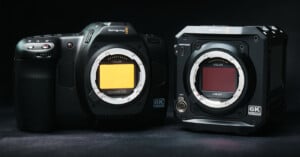 Two Blackmagic 6K cameras are displayed against a dark background. The camera on the left is bulkier with a more extended grip, while the one on the right has a boxy, modular design. Both have Kolar infrared filters attached.