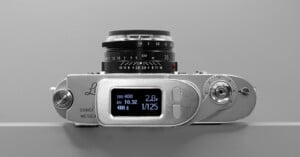 A top view of a vintage camera with a digital display showing settings: ISO 400, EV 10.32, and shutter speed 1/125. The body is metallic with manual dials and a classic lens attached.