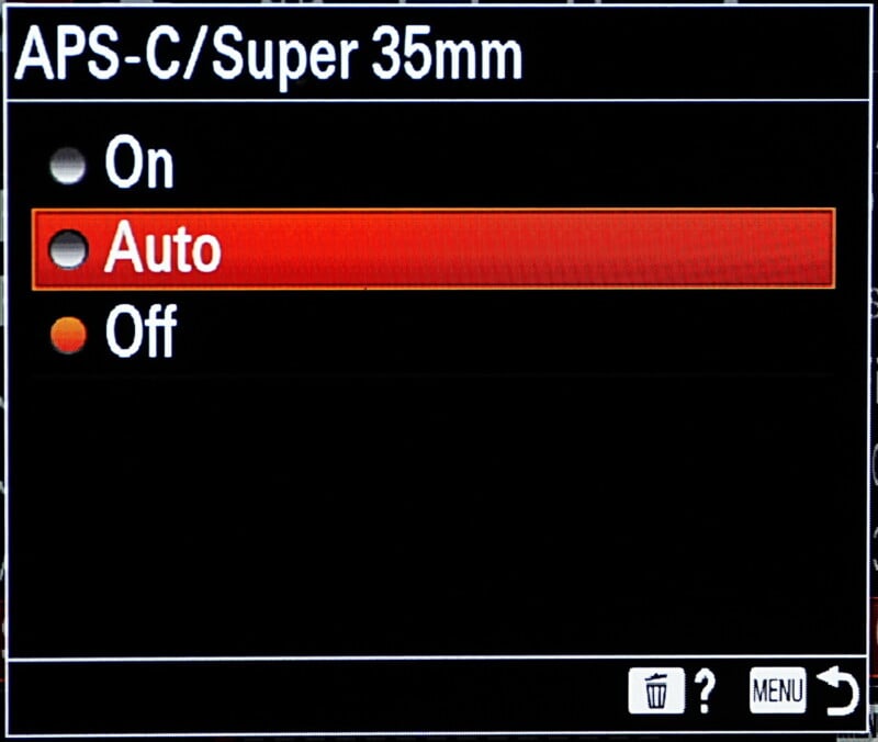 Camera settings menu displaying APS-C/Super 35mm mode options: On, Auto (highlighted in red), and Off. Menu icons include a trash bin, question mark, and return arrow.