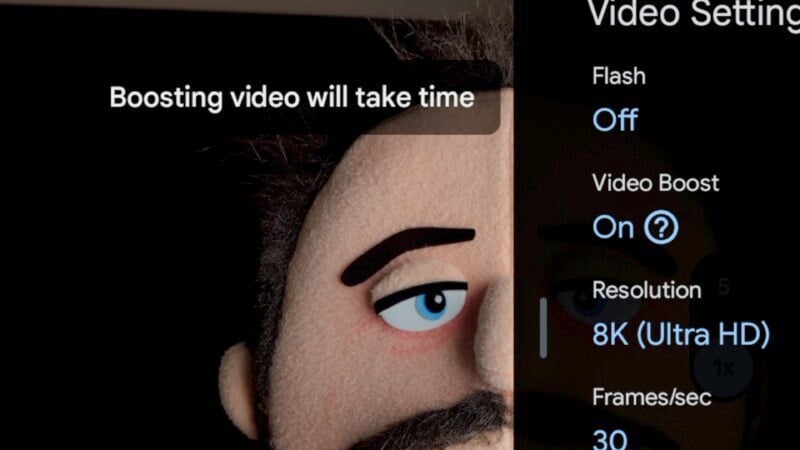 Close-up of a video settings screen, including options for flash (off), video boost (on), resolution (8K Ultra HD), and frames per second (30). The background shows the side of a puppet-like character's face with an alert: "Boosting video will take time.