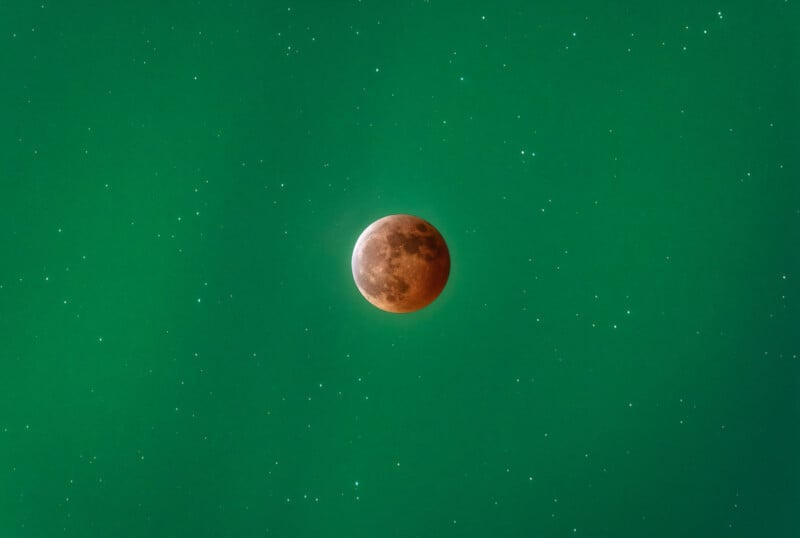 A full moon with a reddish tint is centered against a vibrant teal sky speckled with stars, giving a striking contrast to the celestial scene.