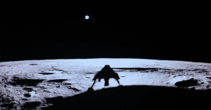 A silhouetted lunar lander is casting a shadow on the moon's surface, which appears illuminated against the dark sky. A small, bright Earth is visible in the background.